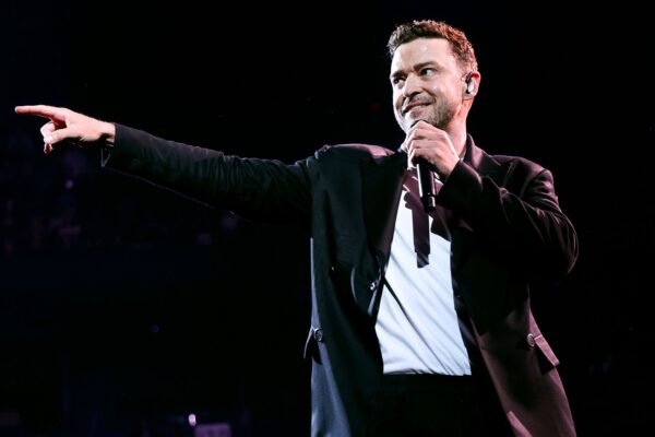 Justin Timberlake tries to get the audience's attention because he's distracted by his phone